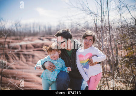 Toddler femmina con la sorella e padre in posa e facce di trazione Foto Stock