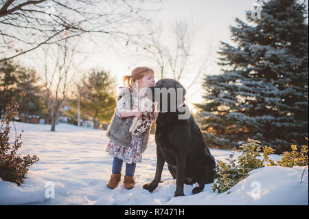 Toddler femmina con i capelli rossi a giocare nella neve con il cane, Keene, Ontario, Canada Foto Stock