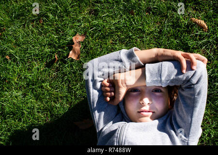 Ragazzo di erba bloccando la luce solare con bracci Foto Stock