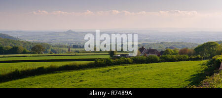 Glastonbury Tor sorge dal paesaggio agricolo di Inghilterra del Somerset livelli come visto da Mendip Hills sopra i pozzetti. Foto Stock