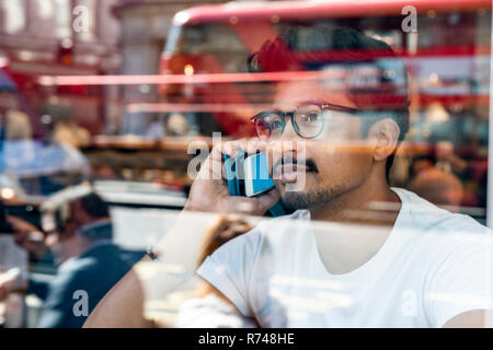 L'uomo utilizza lo smartphone in cafe Foto Stock