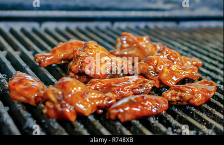 Hot sauced ali di pollo la tostatura sul grill nel ristorante. Chiudere fino in vista laterale. Foto Stock