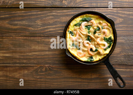 Funghi e spinaci frittata con gamberetti in padella su sfondo di legno con copia spazio. Vista superiore, laici piatta Foto Stock