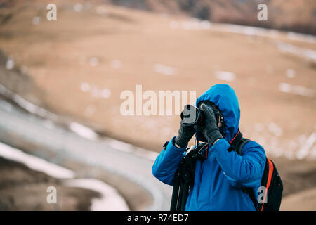 Giovane adulto uomo caucasico turistica viaggiatore Backpacker fotografo a scattare foto foto nel bellissimo paesaggio delle montagne all'inizio dell'inverno. Foto Stock