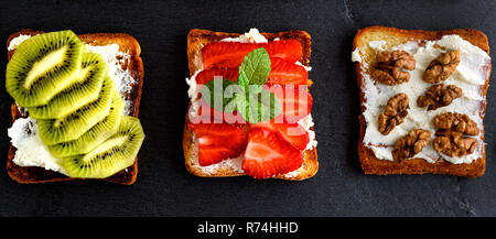 Tre toast con lieve cottage cheese, fragole, kiwi e dadi Foto Stock