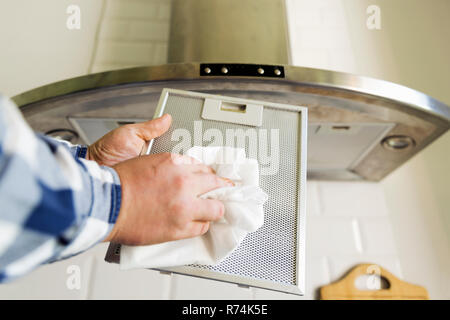 Uomo di pulizia delle mani in maglia di alluminio filtro per cappa. I lavori domestici e di faccende. Cucina cappa sullo sfondo Foto Stock