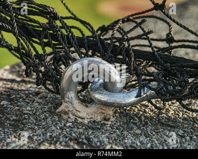 Acciaio corda intrecciata e vite in acciaio occhiello di ancoraggio nel calcestruzzo di base. Alla fine il nodo della fune di acciaio. Foto Stock