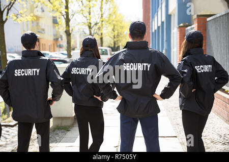 Vista posteriore di guardie di sicurezza in piedi in una riga Foto Stock