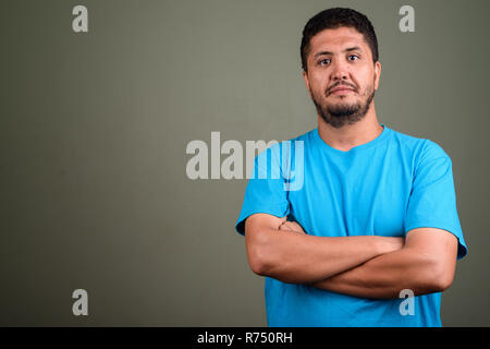 Persiano barbuto uomo che indossa maglietta blu contro backgroun colorati Foto Stock