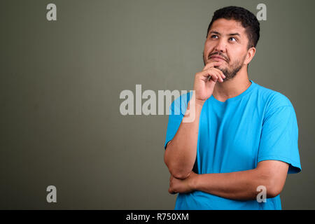 Persiano barbuto uomo che indossa maglietta blu contro backgroun colorati Foto Stock