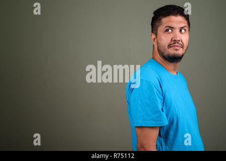 Persiano barbuto uomo che indossa maglietta blu contro backgroun colorati Foto Stock