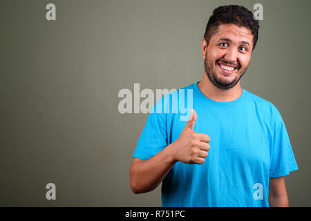 Persiano barbuto uomo che indossa maglietta blu contro backgroun colorati Foto Stock