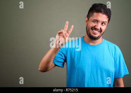 Persiano barbuto uomo che indossa maglietta blu contro backgroun colorati Foto Stock