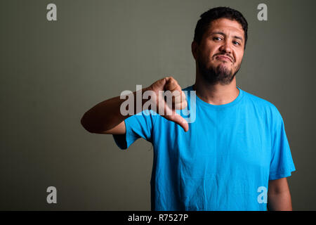 Persiano barbuto uomo che indossa maglietta blu contro backgroun colorati Foto Stock