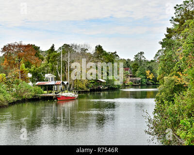 Rosso unica barca a vela legata a un piccolo molo sul Eslava succursale o il Bayou in South Alabama, Stati Uniti d'America. Foto Stock