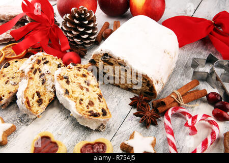 Europeo tradizionale pasticceria di Natale, fragrante cotto domestico stollen con spezie e frutta secca. Affettare sul tavolo rustico con il natale a rami di alberi e de Foto Stock