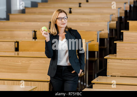 Insegnante femminile in abbigliamento formale azienda apple in aula Foto Stock