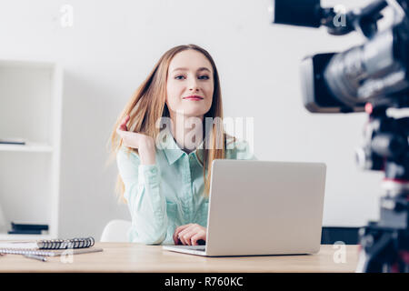 Sorridente femmina attraente video registrazione blogger vlog in ufficio e guardando la fotocamera Foto Stock