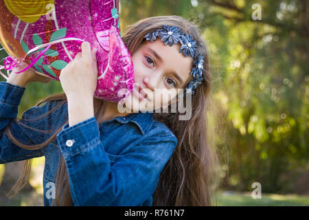 Carino giovane razza mista Ragazza con palloncino in Mylar all'esterno. Foto Stock