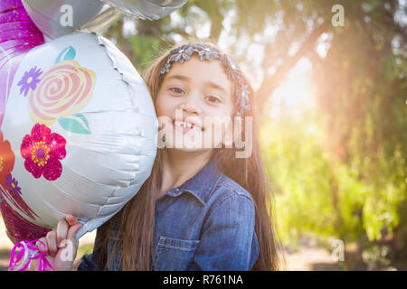 Carino giovane razza mista Ragazza con palloncino in Mylar all'esterno. Foto Stock