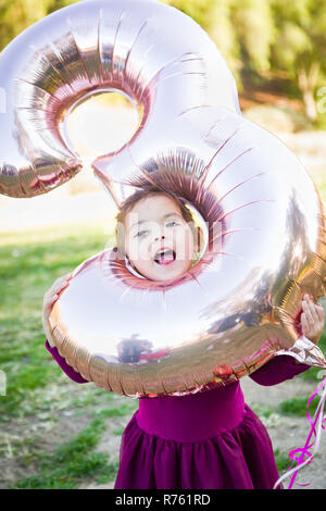 Carino Bambina giocando con il numero tre del palloncino in Mylar all'esterno. Foto Stock