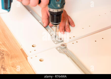 Assemblaggio di mobili di truciolare, utilizzando un cacciavite a batteria Foto Stock