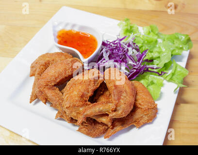 Pollo fritto ala / pastella fritto di pollo croccante sulla piastra bianca e insalata di lattuga viola vegetale di cavolo e peperoncino salsa piccante - pollo fritto ala Foto Stock