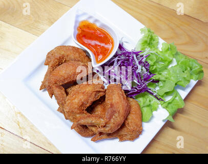 Pollo fritto ala / pastella fritto di pollo croccante sulla piastra bianca e insalata di lattuga viola vegetale di cavolo e peperoncino salsa piccante - pollo fritto ala Foto Stock