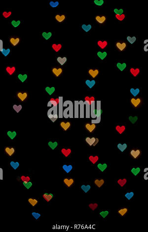 A forma di cuore ad qustom bokeh creato da luci di decorazione e isolate su sfondo nero. Foto Stock