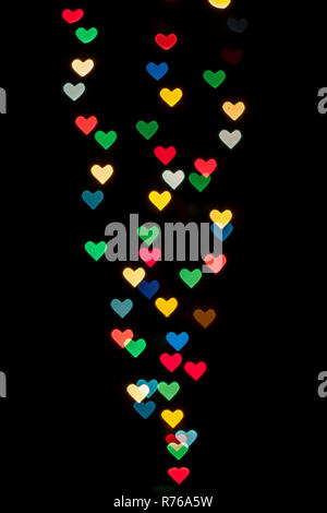 A forma di cuore ad qustom bokeh creato da luci di decorazione e isolate su sfondo nero. Foto Stock
