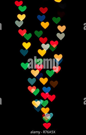 A forma di cuore ad qustom bokeh creato da luci di decorazione e isolate su sfondo nero. Foto Stock