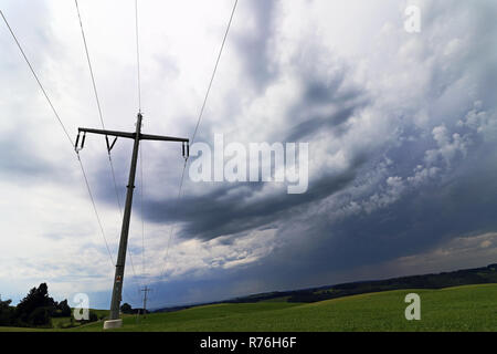 Una tempesta a himmer al di sopra di un traliccio di elettricità. oscura pioggia nuvole nel cielo su una linea di alimentazione Foto Stock