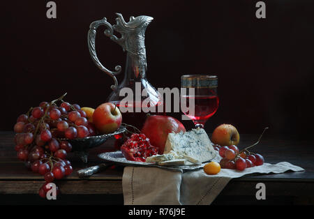 Vino rosso con formaggio blu, limone uva e melograno Foto Stock