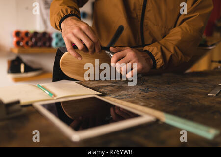 Uomo che ripara skateboard in officina Foto Stock