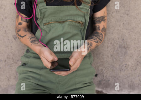 Donna che utilizza il telefono cellulare a skate park Foto Stock