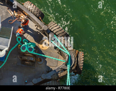 Overhead POV vista del rimorchiatore a traino, funi e lavoratori assistere grandi navi di attraccare in venti alti su un luminoso giorno di sole. Canale Gastineau, Juneau, Alaska, U Foto Stock