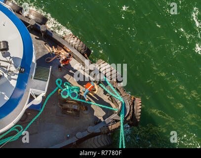 Overhead POV vista del rimorchiatore a traino, funi e lavoratori assistere grandi navi di attraccare in venti alti su un luminoso giorno di sole. Canale Gastineau, Juneau, Alaska, U Foto Stock