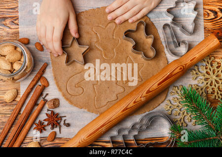 Il bambino con le mani in mano rende di panpepato tradizionali. Spezie sul tavolo-anice, il cardamomo, la cannella, i chiodi di garofano, noce moscata, mandorle. Pasta cruda e Clippers in forma Foto Stock