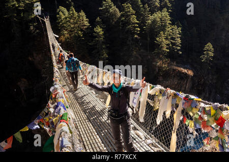 Il Nepal, Larja Dobhan, senior turista femminile celebrando attraversamento Larja superiore sospensione ponte sul Dudh Khosi river Foto Stock