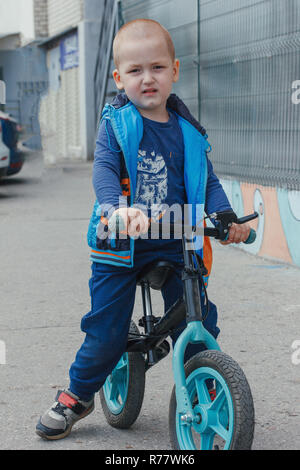 Little Boy a cavallo di un equilibrio in bici lungo il percorso nella corte interna su una soleggiata giornata estiva Foto Stock