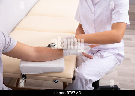 Close-up di medico bendaggio di legatura sull uomo ferito la mano in clinica Foto Stock