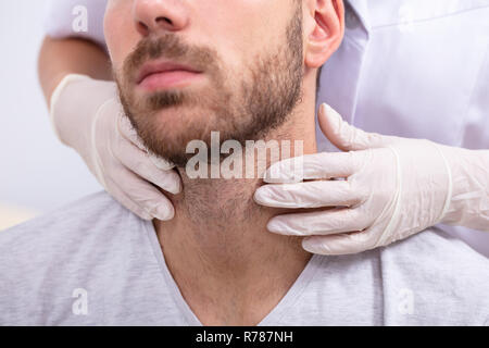 Medico la mano indossando i guanti di eseguire esame fisico palpazione della ghiandola tiroide Foto Stock