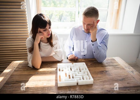 Due imprenditori contemplato risolvendo puzzle Maze Foto Stock