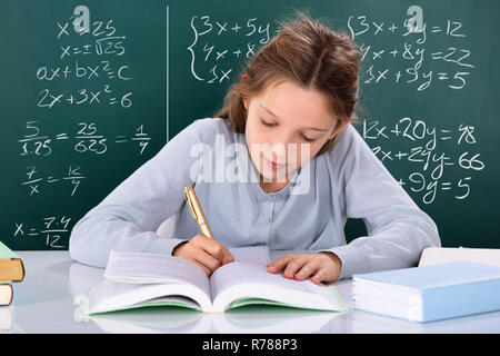 Ritratto di una ragazza facendo studio nella parte anteriore del Green Chalkboard Foto Stock