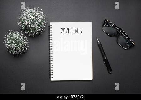 2019 nuovi anni di risoluzioni di composizione. Aprire blank notebook, penna e mini albero di natale in toni di nero. Festa di Natale e Anno Nuovo concetto. Parte superiore Foto Stock