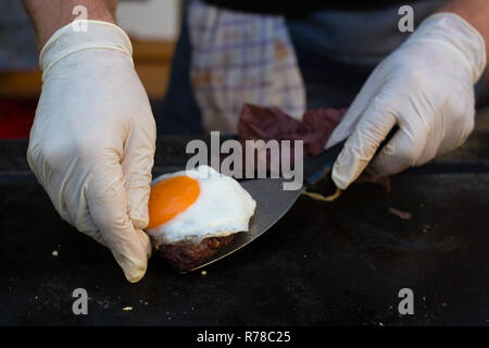 Lo Chef rendendo hamburger di manzo all'aperto sulla cucina aperta International Food festival evento. Foto Stock