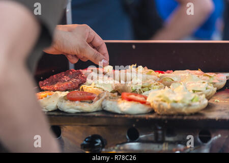 Lo Chef rendendo hamburger di manzo all'aperto sulla cucina aperta International Food festival evento. Foto Stock