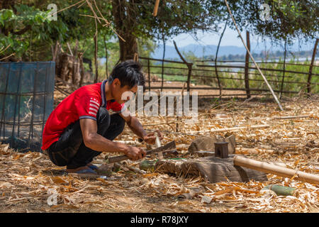 Don Daeng, Laos - Aprile 27, 2018: Locale uomo taglio del legno in una remota area selvaggia rurali del Laos Foto Stock