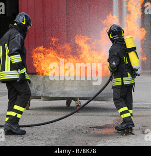 Due vigili del fuoco con bombole ossigeno spegnere il fuoco durante un esercizio di formazione Foto Stock