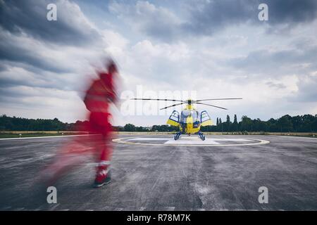 Allarme per elicottero il servizio di emergenza medica. Paramedic in esecuzione su un elicottero su un eliporto. Foto Stock